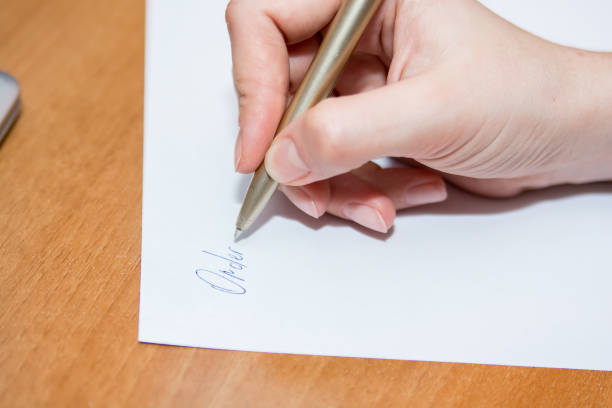 istock Close up hand with pen writes on paper on desk 903744474
