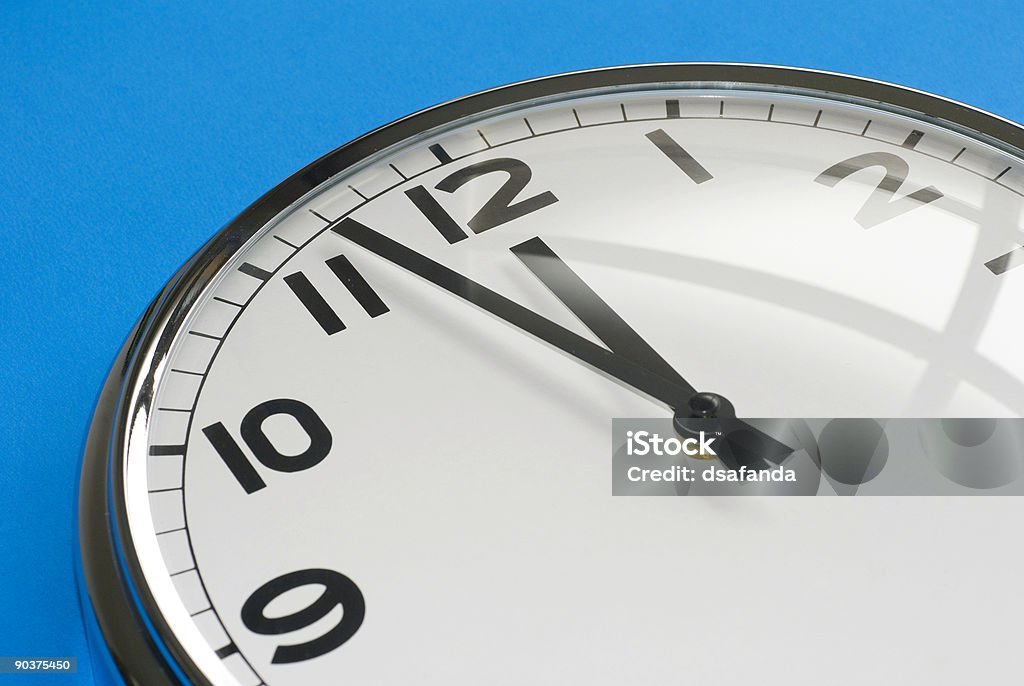 Time#1 A clock face with hour and minute hands approaching 12:00. Anticipation Stock Photo