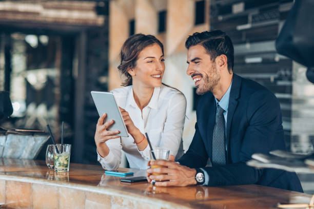 On a business trip together Couple of business persons having drinks and looking at a digital tablet in the lobby woman necktie stock pictures, royalty-free photos & images