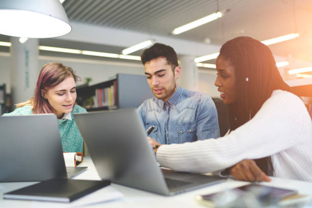 istock Talented young journalist working on creation article for online issue talking to each other sitting in office,male and female students doing homework task searching information for project via laptop 903762936