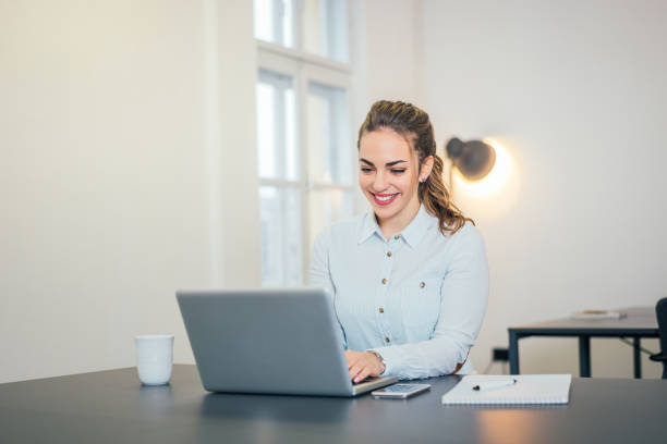 istock Young cheerful woman working on laptop in the office. 903764242