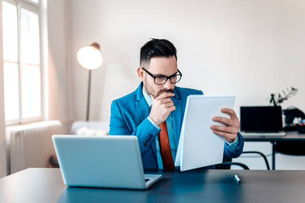 istock Concentrated young businessman reading documents at office desk. 903764606
