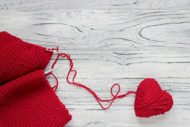 Heart in the form of a string of threads from which a red sweater knits. Valentines day concept. Heart in the form of a string of threads from which a red sweater knits. Valentines day concept. knitting textile wool infinity stock pictures, royalty-free photos & images