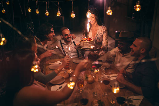 Multi-ethnic friends celebrating birthday at rustic cottage party in village Young multi-ethnic friends celebrating birthday with birthday cake at elegant rustic house dinner party plus size woman fashion laughing stock pictures, royalty-free photos & images