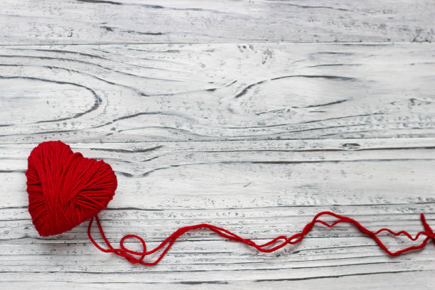 Heart in the form of a string of threads from which a red sweater knits. Valentines day concept. Heart in the form of a string of threads from which a red sweater knits. Valentines day concept. knitting textile wool infinity stock pictures, royalty-free photos & images