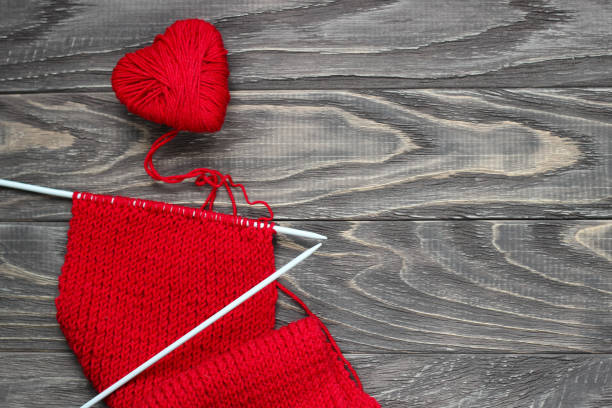 Heart in the form of a string of threads from which a red sweater knits. Valentines day concept. Heart in the form of a string of threads from which a red sweater knits. Valentines day concept. knitting textile wool infinity stock pictures, royalty-free photos & images