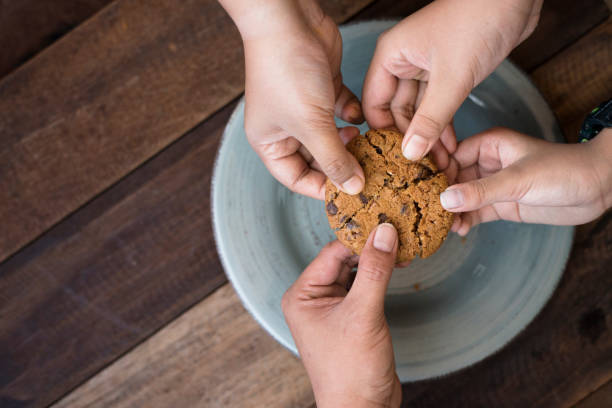 istock Close-Up Of Hands Holding Cookie Over Plate 903780298