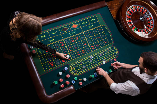 Croupier and woman player at a table in a casino. Picture of a c Croupier and woman player at a table in a casino. Picture of a classic casino roulette wheel. Gambling. Casino. Roulette. Poker. Top view of a green roulette table token photos stock pictures, royalty-free photos & images