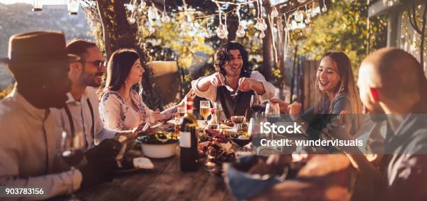 Young Multiethnic Friends Dining At Rustic Countryside Restaurant At Sunset Stock Photo - Download Image Now
