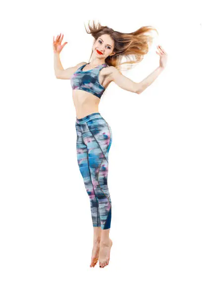 young beautiful woman in color-blue top and leggings jumping of joy. Young sporty fit emale model isolated on white background in full body