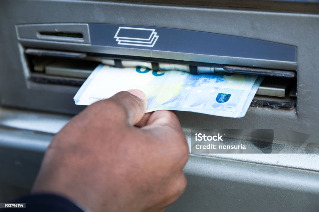 Close up of man taking cash from ATM with credit card. ATM Stock Photo