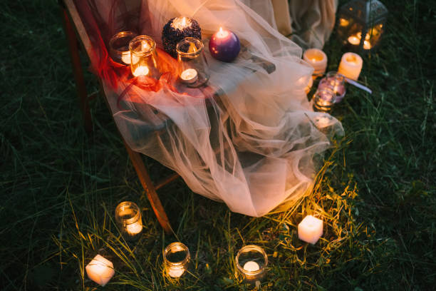 ночные изысканные детали свадьбы на открытом воздухе: летняя или весенняя церемония с низким освещением свечей, стоящих на стуле, покрытом  - lowlight стоковые фото и изображения