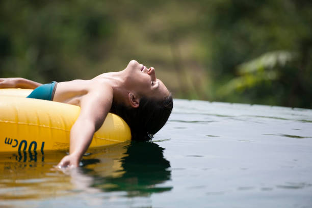 Sunbathing while floating on inflamable ring Young female floating on water in inflamable ring, eyes closed inflamable stock pictures, royalty-free photos & images