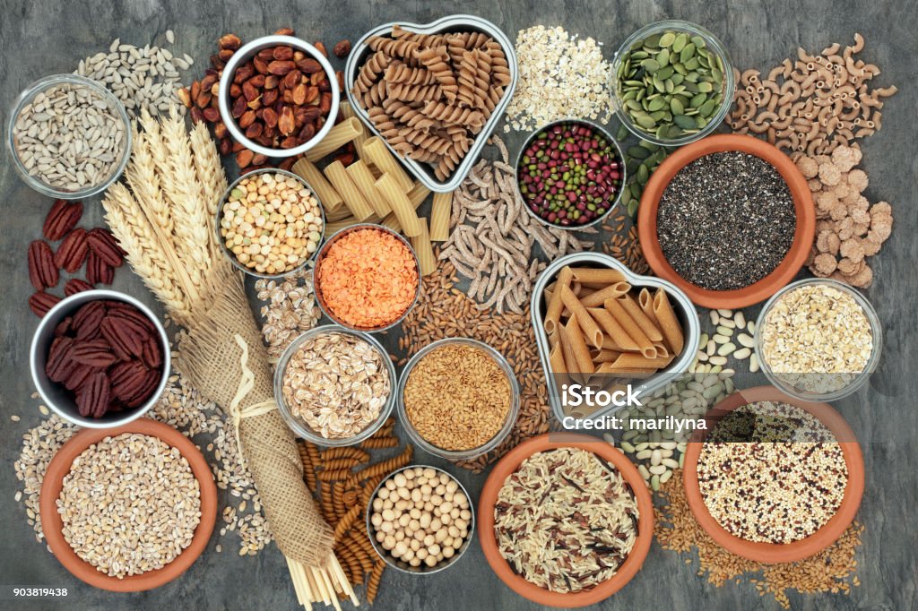 Healthy High Fibre Food Healthy high fibre dietary food concept with whole wheat pasta, legumes, nuts, seeds, cereals, grains and wheat sheaths. High in omega 3, antioxidants, vitamins. On marble background top view. Wholegrain Stock Photo