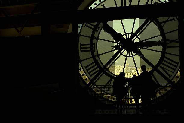 Sightseeing Paris. Views from Orsay museum. Three people looking at Paris' skyline through the clock located in Orsay Museum. musee dorsay stock pictures, royalty-free photos & images