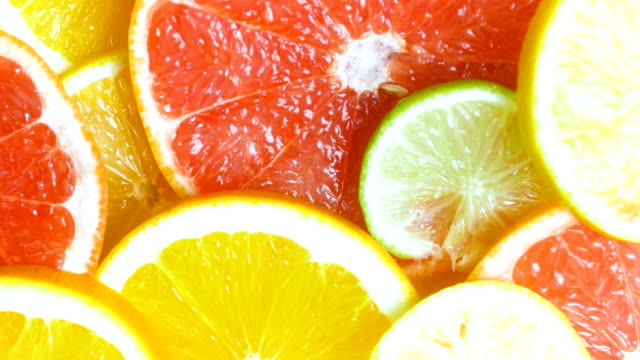 View from top of camera panning along assortment of citrus slices lying on table