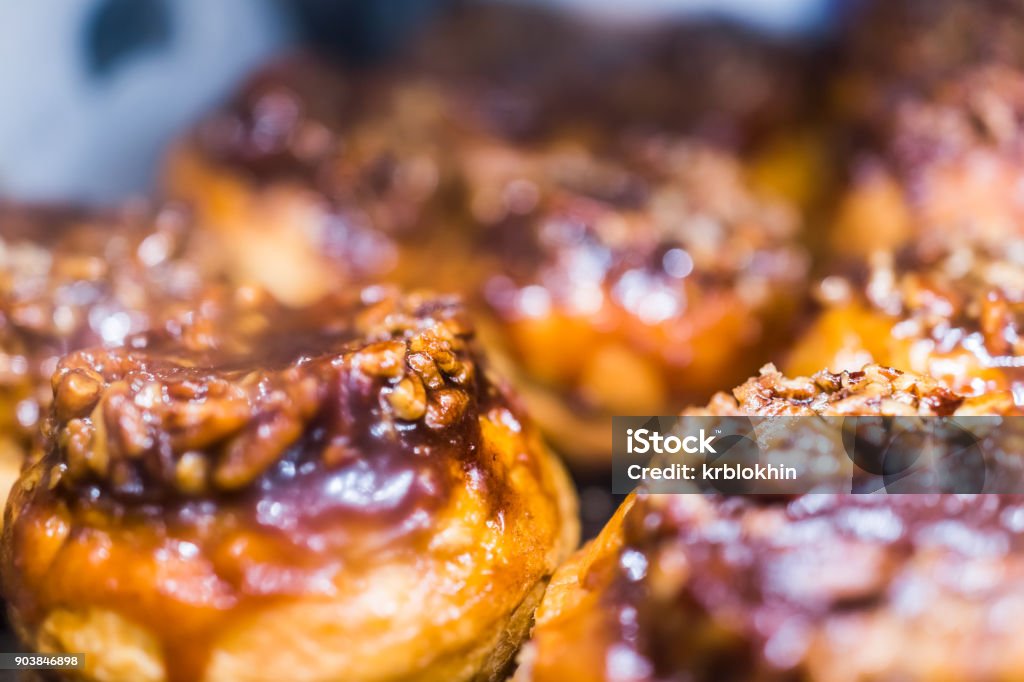 Macro closeup display of chocolate drizzled pecan nut sticky buns danish pastries caramelized in bakery for breakfast Sticky Bun Stock Photo