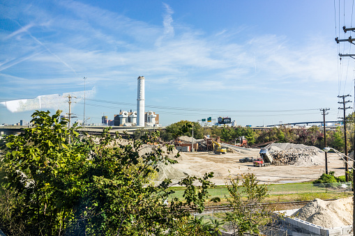 Baltimore: Industrial factory with sign and smoke pollution with landfill mound construction
