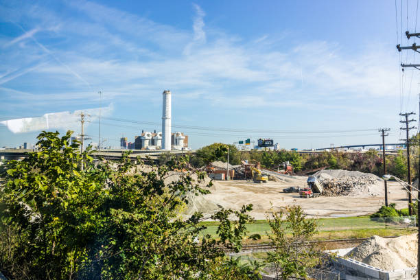 industrial factory with sign and smoke pollution with landfill mound construction - 5515 imagens e fotografias de stock