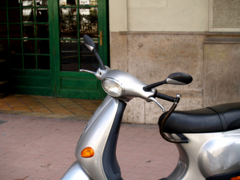 A scooter sits outside a green door. Spain