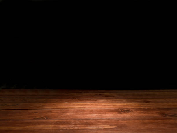 Wooden empty table Wooden empty table (reddish brown rustic wood) with spotlight. Dark (black) background. Ideal for photo montage. No people. Horizontal orientation. mahogany photos stock pictures, royalty-free photos & images