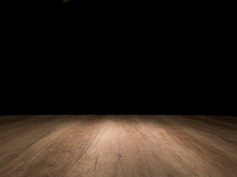 Wooden empty table with spotlight. Dark background. Ideal for photo montage. No people. Horizontal orientation. Front view.