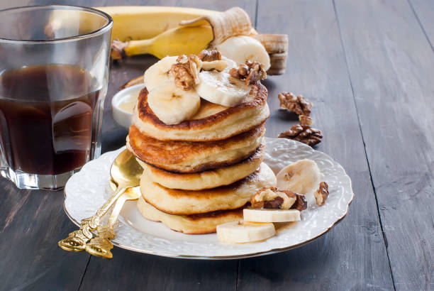 istock Pancakes with banana, nuts ,honey and cup coffee on dark background 903870388