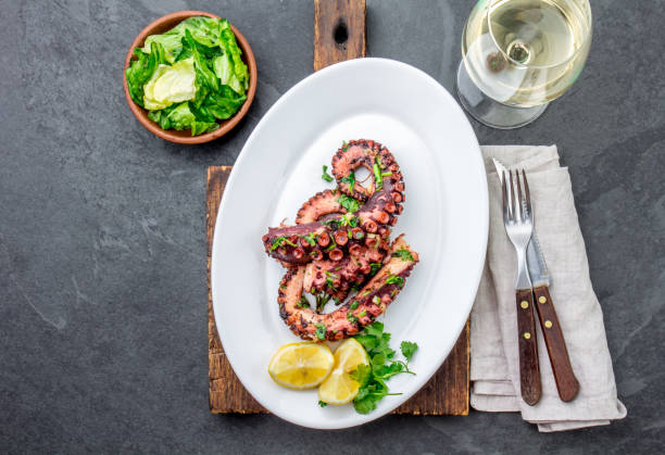 Grilled octopus on white plate serverd with white wine , top view. Seafood stock photo