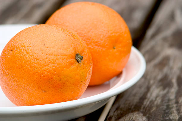 istock Two oranges on a white plate and wooden table 90387437