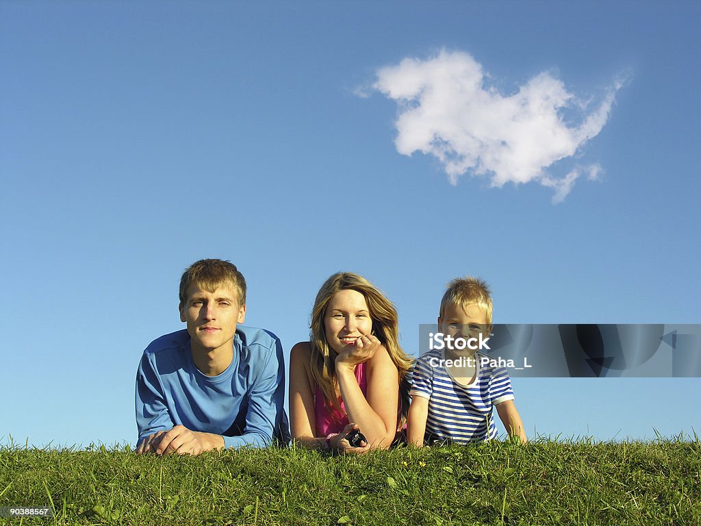 Familia en hierba bajo cielo azul - Foto de stock de Acostado libre de derechos