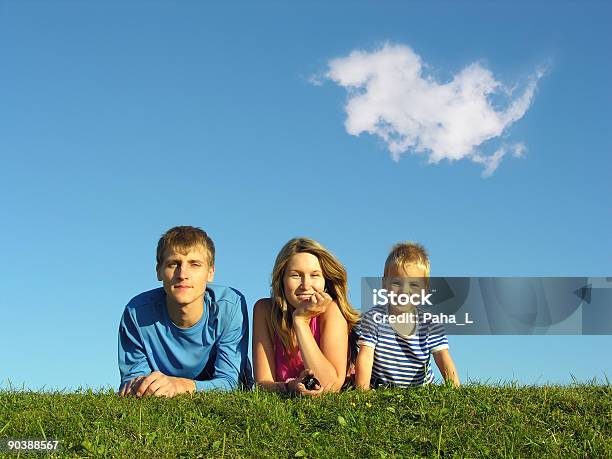 Familia En Hierba Bajo Cielo Azul Foto de stock y más banco de imágenes de Acostado - Acostado, Aire libre, Alegría