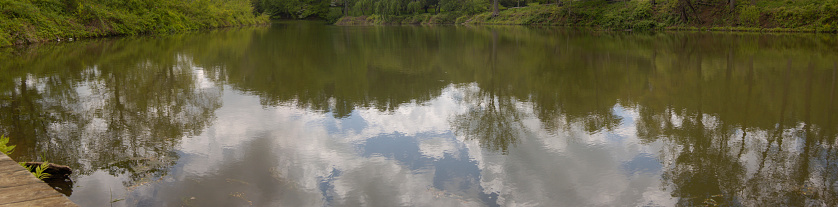 Trees and the summer afternoon sky are beautifully reflected in the pond at Holmdel Park