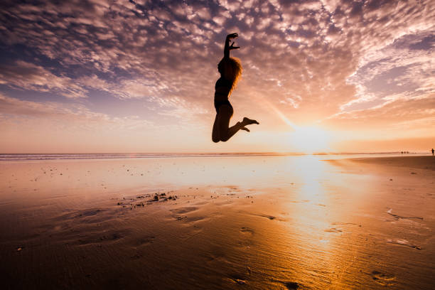istock Attractive silhouette jumping on the beach at sunrise. 903896386