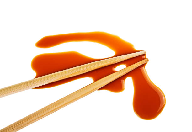Splashes of soy sauce and chopsticks isolated on white background