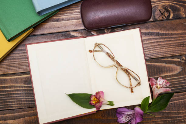 istock Open notebook with flowers and spectacles on a wooden table, top view. 903907586