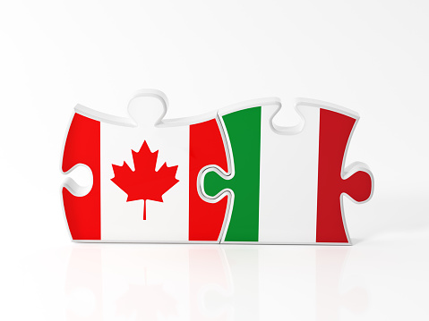 Jigsaw puzzle pieces textured with Canadian and  Italian flags on white. Horizontal composition with copy space. Clipping path is included.
