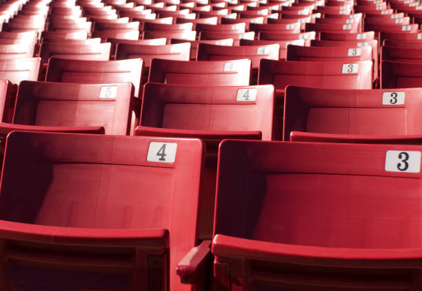 Red stadium seats located at an outdoor sports and entertainment venue. Sharp focus upfront with background seats blurred.