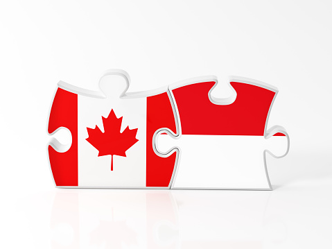 Jigsaw puzzle pieces textured with Canadian and Monaco flags on white. Horizontal composition with copy space. Clipping path is included.