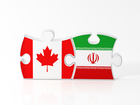 Jigsaw puzzle pieces textured with Canadian and Iranian flags on white. Horizontal composition with copy space. Clipping path is included.