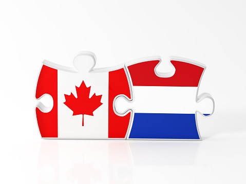 Jigsaw puzzle pieces textured with Canadian and Dutch flags on white. Horizontal composition with copy space. Clipping path is included.