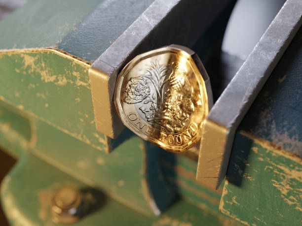 British pound coin held by a vice/clamp Close-up of the a British pound coin held by a bench vice or clamp. pressure point photos stock pictures, royalty-free photos & images