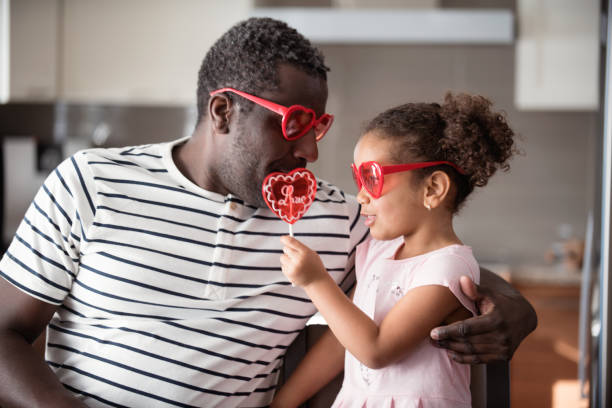 istock Mixed race Father and daughter taste lollipop during Valentine's Day 903926440