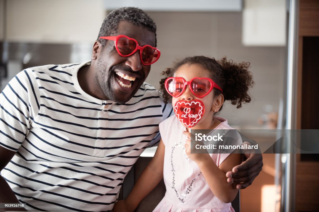 Mixed race Father and daughter taste lollipop during Valentine's Day Mixed race Father and daughter taste lollipop during Valentine's day with parents, family multi-ethnic of all ages and mixed race couple. Using heart shapes lollipop with the word Love print on. Photos was taken in Quebec Canada. Valentine's Day - Holiday Stock Photo