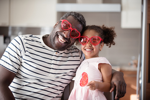 Mixed race Father and daughter taste lollipop during Valentine's day with parents, family multi-ethnic of all ages and mixed race couple. Using heart shapes lollipop with the word Love print on. Photos was taken in Quebec Canada.