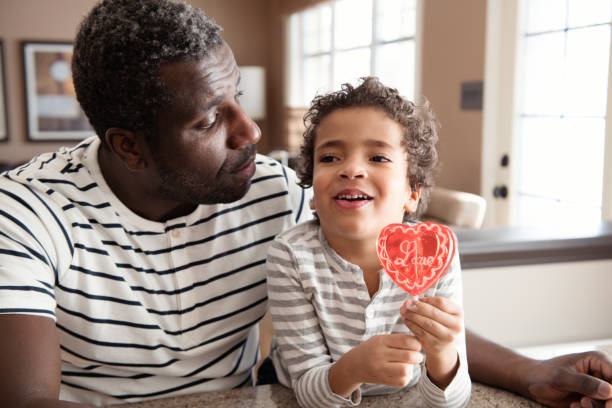 istock Mixed race Father and son taste lollipop during Valentine's Day 903927476