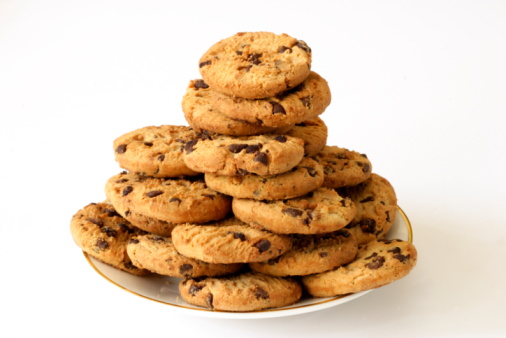 Pile of chocolate chip cookies on a plate aganist a white background.