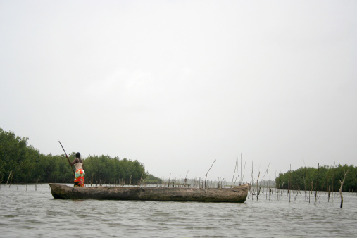 Young girl riding a wooden canoe alone in the Guamá River, part of the Amazon River, near Belém, Pará, Amazon, Brazil. January, 2008.