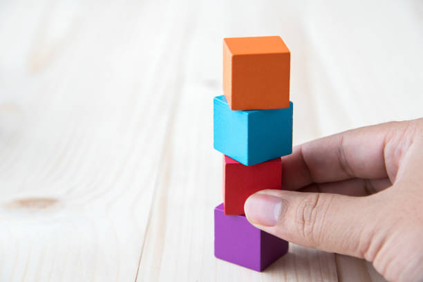 istock Close-Up Of Hand Holding Multi Colored Blocks On Table 903960458