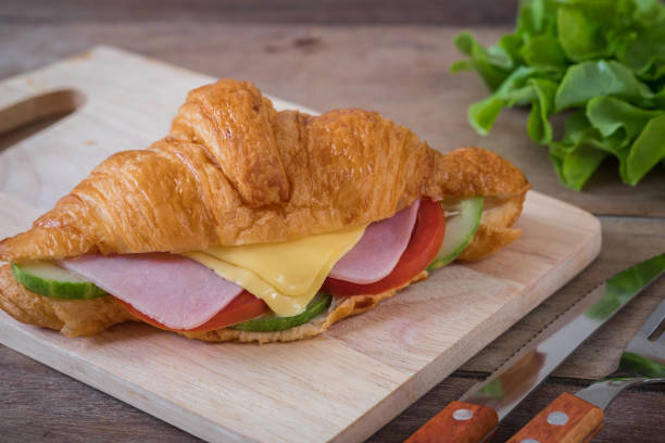 istock Croissant with ham, cheese and vegetable on wooden board 903964756