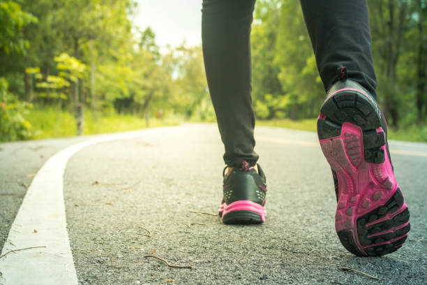 istock Low Section Of Woman Running On Road Amidst Trees 903968762
